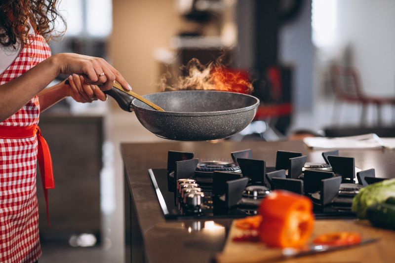 chef-de-mulher-cozinhar-legumes-na-panela-1 Fogão Elétrico vs. Fogão a Gás: Qual é o Mais Econômico e Eficiente?